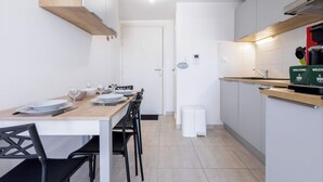 A modern kitchen with a wooden countertop, white cabinets, and a dining area with chairs and a table set for two.
