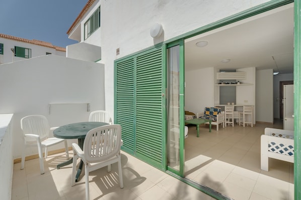 A patio with a table and chairs, a sliding glass door, and a small dining area with a table and chairs.