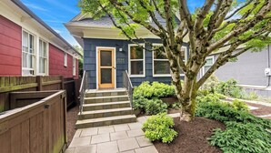 A residential house with a front door, steps, and a tree in the yard. - Broadway & Bloom | Luxe Stay (Seattle)
