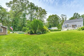 A large house with a well-maintained lawn, a swimming pool, and a flag. - Pool, Sunroom & Gardens: Luxe Sandy Hook Home! (Sandy Hook)