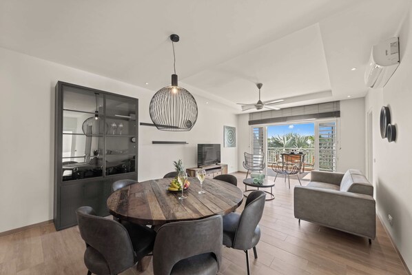 A modern dining area with a wooden table, dark chairs, and pendant lighting.