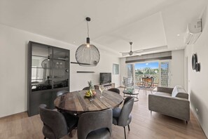Un comedor moderno con mesa de madera, sillas oscuras e iluminación colgante.