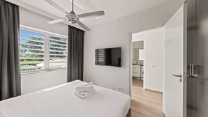 Une chambre d’hôtel équipée d’un lit, d’un ventilateur de plafond, d’un téléviseur à écran plat et offrant une vue sur l’extérieur.