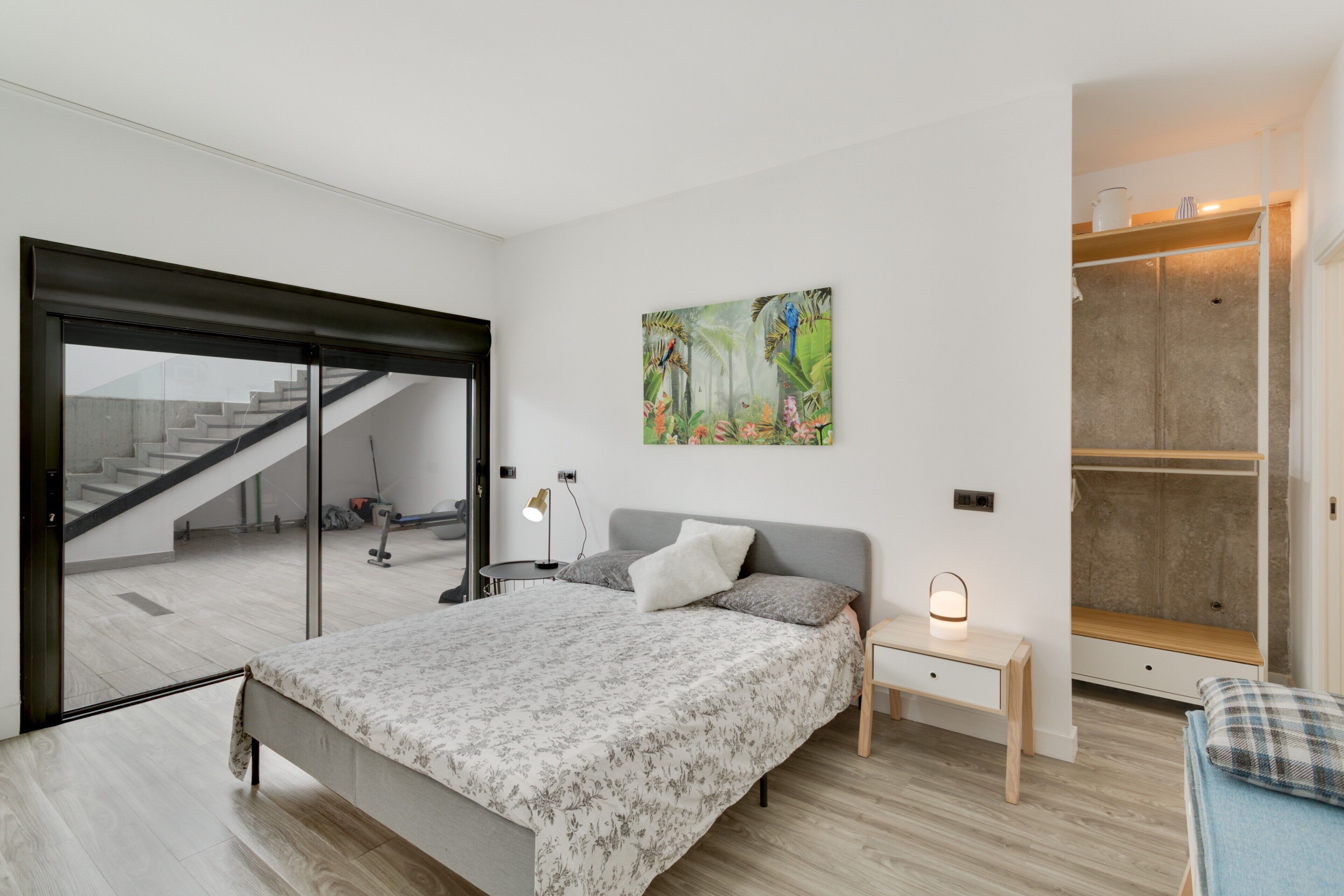 A bedroom with a bed, bedside table, lamp, and a painting on the wall.