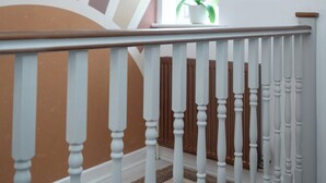 Una escalera con balaustres blancos y alfombra color beige.