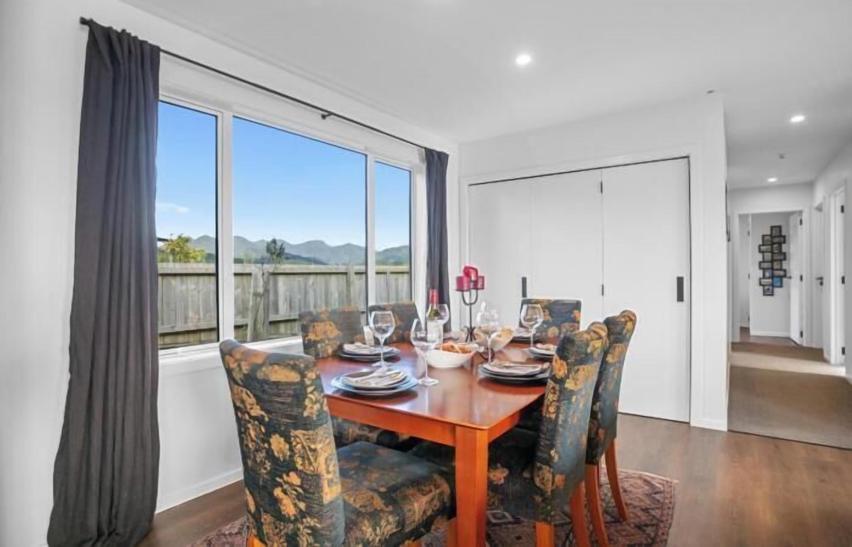 A dining area with a table set for four, large windows, and a view of mountains.