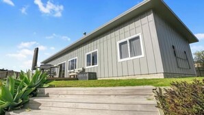 A single-story house with a grey exterior, a front porch, and a clear blue sky.