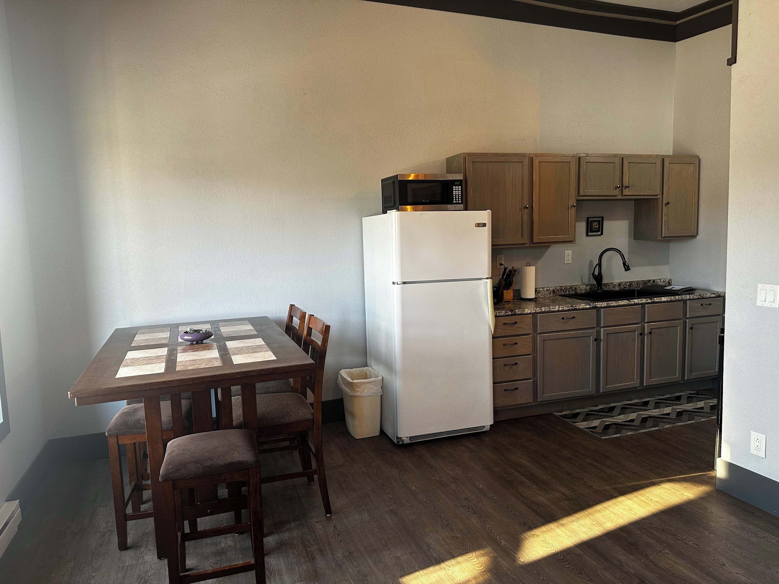 A compact kitchen with a refrigerator, microwave, and wooden cabinets.
