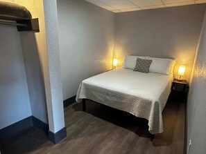 Una cama individual con colcha, dos lámparas de noche y una mesita de noche.
