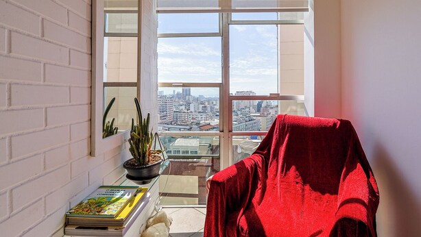 A balcony with a red chair, a potted plant, and a book. - Apto Pet-friendly com Garagem e Vista de Botafogo (Rio de Janeiro)