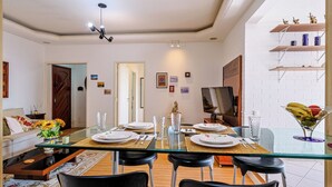 A dining area with a glass table, black chairs, and a TV on the wall. - Apto Pet-friendly com Garagem e Vista de Botafogo (Rio de Janeiro)