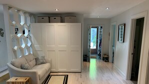 Un salon moderne avec un canapé beige, une caisse en bois et une armoire blanche.