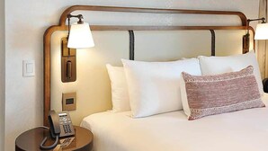 A hotel room with a wooden headboard, a bedside lamp, a telephone, and a bed with white and patterned pillows. - Corazon Cabo Resort & Spa - Oceanfront infinity pools, beach club, rooftop bar, (Cabo San Lucas)