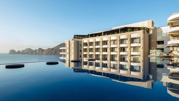 A modern hotel with a pool reflecting the building and surrounding landscape. - Corazon Cabo Resort & Spa - Oceanfront infinity pools, beach club, rooftop bar, (Cabo San Lucas)