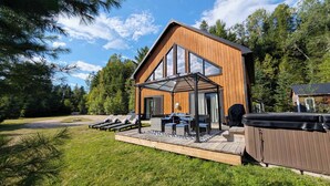 Een moderne houten blokhut met een terras, buiten zitplaatsen en een overdekte patio.