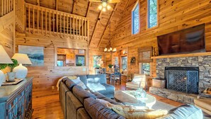 A spacious wooden interior with a stone fireplace, a large sofa, and a dining area. - Secluded 3 Bedroom Cabin w/hot tub in the mountains of Clayton, Ga (Clayton)