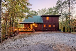 Eine Hütte mit Veranda, überdachter Terrasse und umzäunter Garten.