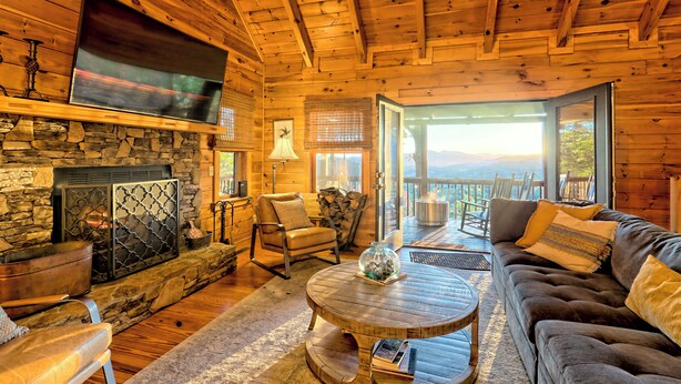 A cozy cabin interior with a stone fireplace, wooden ceiling, comfortable seating, and a large TV. - Secluded 3 Bedroom Cabin w/hot tub in the mountains of Clayton, Ga (Clayton)