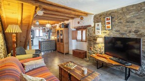 A cozy living room with a wooden ceiling, a stone wall, a television, and a chessboard. - La Pelotilla Genalguacil by Ruralidays (Málaga)
