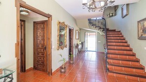 A spacious hallway with a wooden door, a mirror, and a staircase leading to an upper floor.