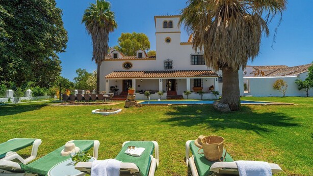 A villa with a pool, outdoor seating, and a well-maintained lawn.