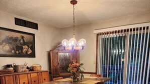Ein Essbereich mit Holztisch, Stühlen, einer Chandelierleuchtre, einem Schrank und einem Gemälde an der Wand.