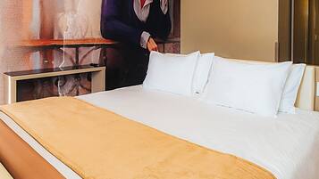 A hotel room with a large bed, a bedside table, and a wall mural.