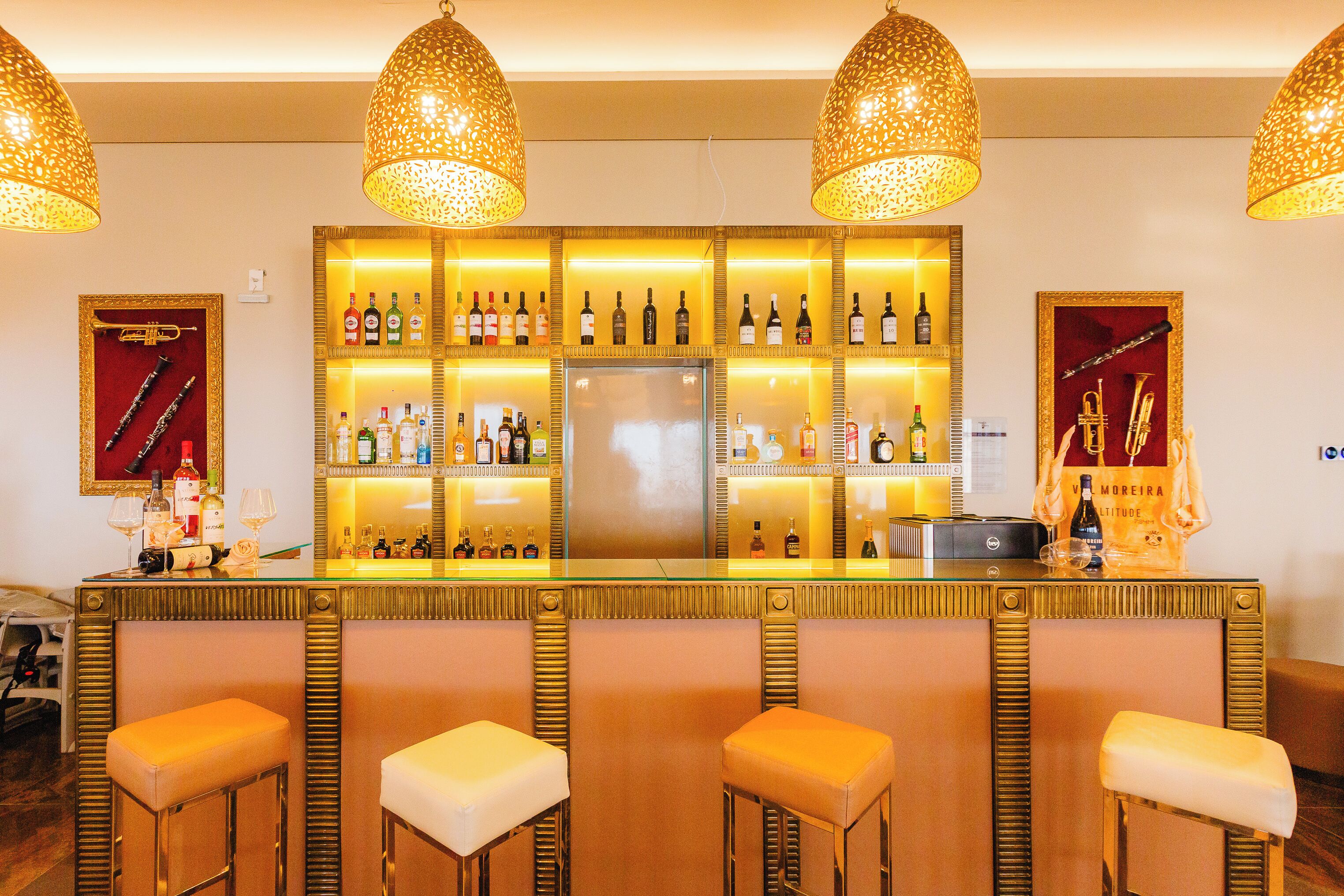 A bar area with a central counter, multiple stools, and overhead lighting fixtures.