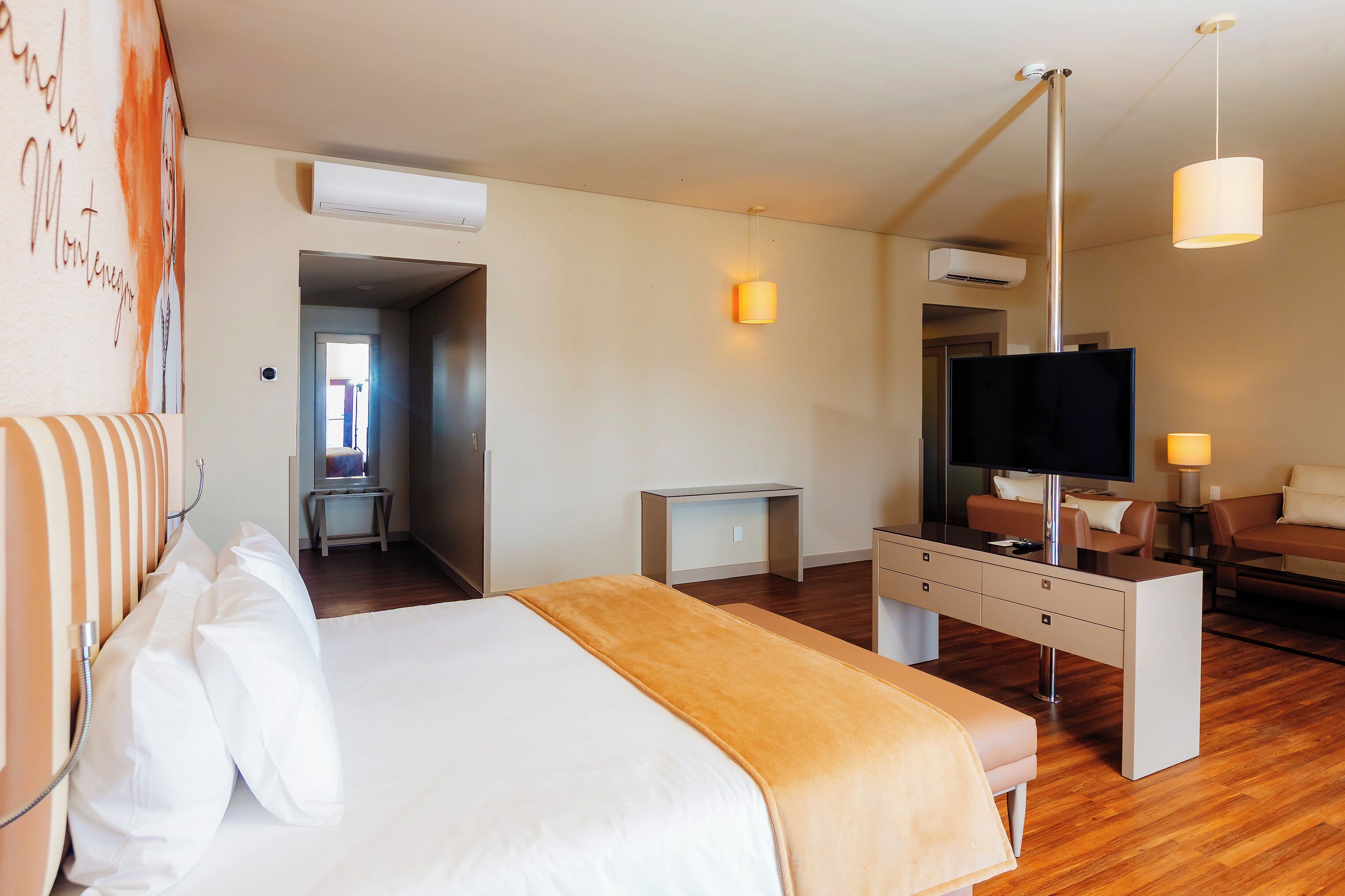 A hotel room with a bed, a desk, a television, and a seating area.