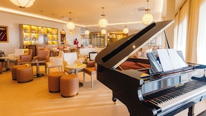 Ein Flügel in einer hell erleuchteten Lounge mit Sitzgelegenheiten und einer Bar im Hintergrund.