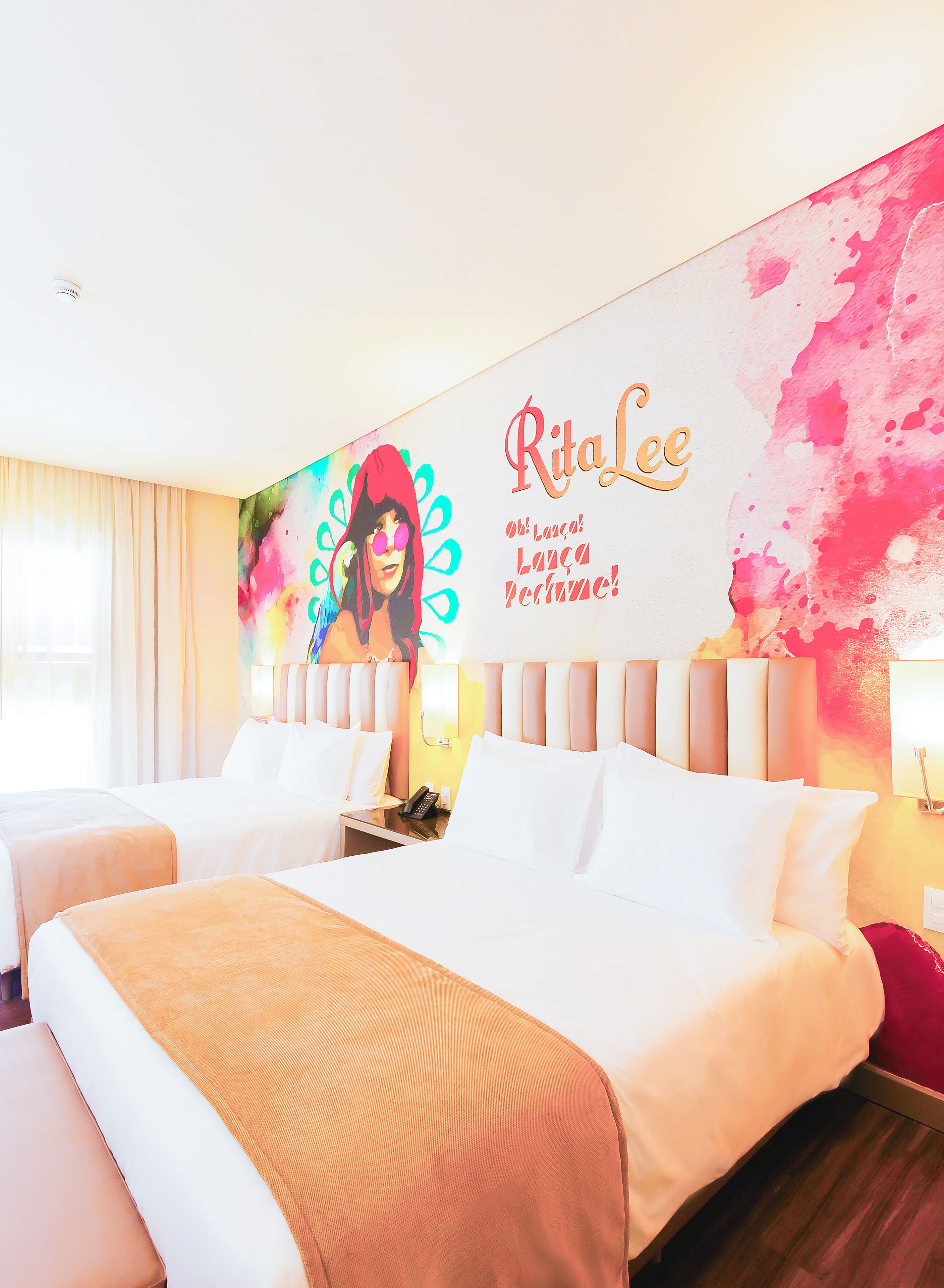 A hotel room with two beds, a large wall mural, and a window with curtains.