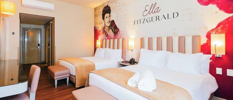 A hotel room with two beds, a sitting area, and a large portrait on the wall.