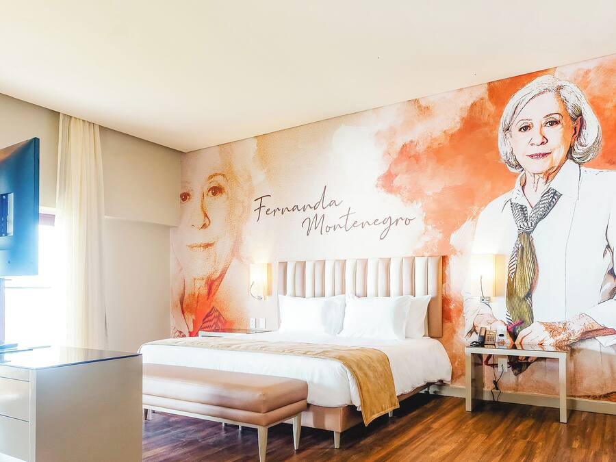 Ein Hotelzimmer mit Bett, Nachttisch und Wandgemälde.
