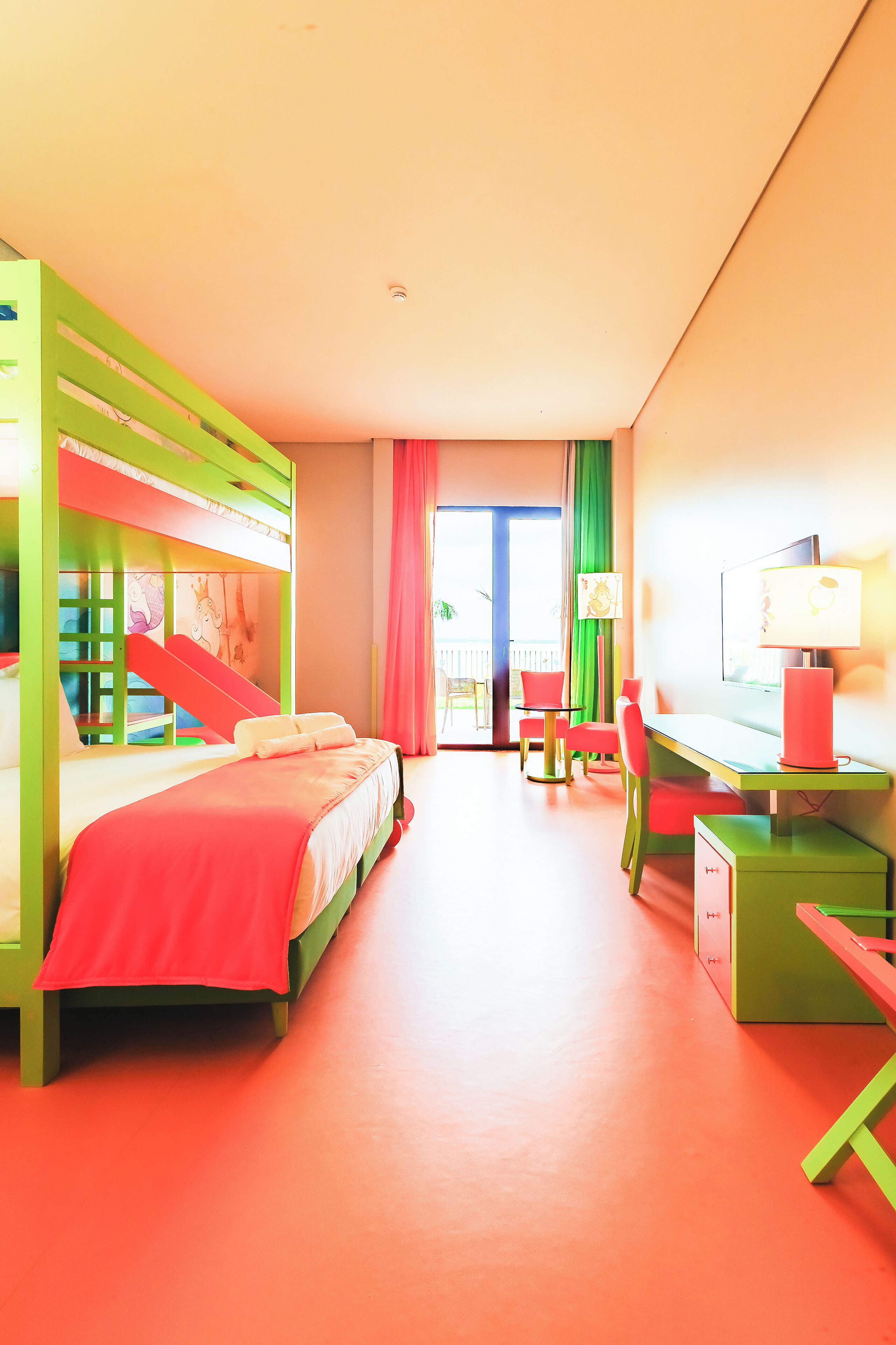 Habitación de hotel de colores brillantes con literas, un escritorio y una silla.