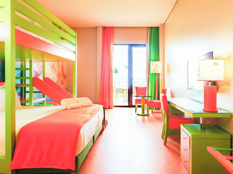 Habitación de hotel de colores brillantes con literas, un escritorio y una silla.