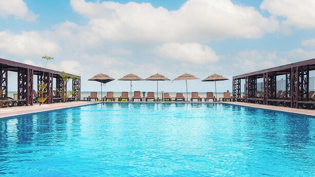 Ein Swimmingpool mit Liegestühlen und Sonnenschirmen, umgeben von Holzbauten.