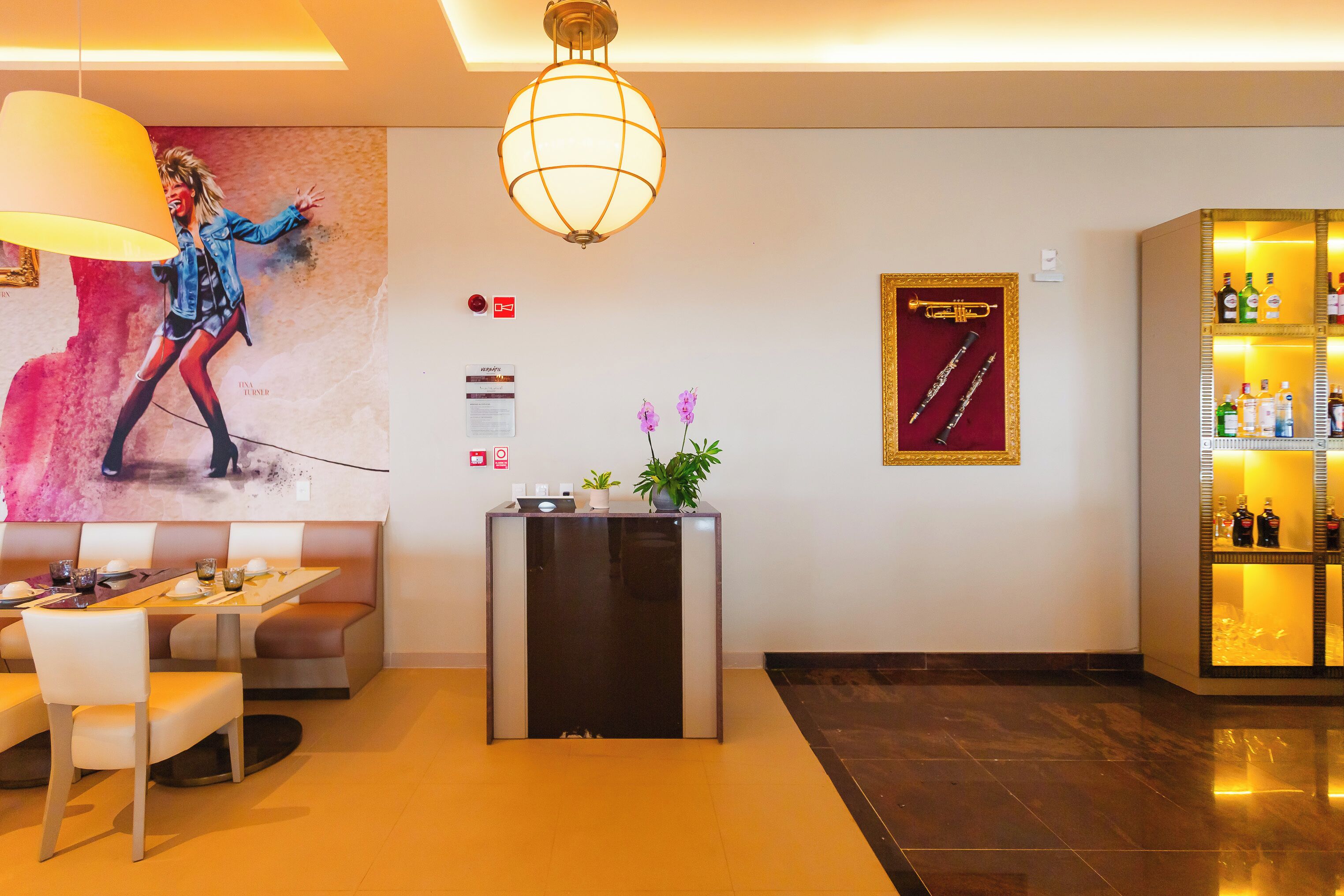 A hotel lobby with a reception desk, seating area, decorative wall art, and a bar area.
