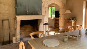 A rustic interior with a stone fireplace, wooden beams, and a dining area with chairs and a table. - Serene villa with heated and covered pool in Le Brévedent (Le Brévedent)