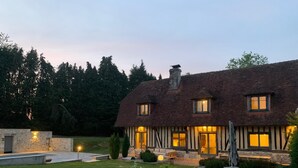 A two-story house with a dark tiled roof, a stone chimney, and a well-maintained garden with a lawn and shrubs. - Serene villa with heated and covered pool in Le Brévedent (Le Brévedent)