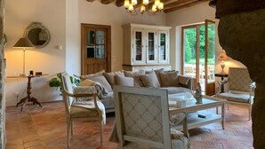 A rustic living room with exposed wooden beams, a large sofa, two armchairs, a patterned table, and a cabinet with glass doors. - Serene villa with heated and covered pool in Le Brévedent (Le Brévedent)