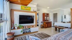 Una sala de estar moderna con televisor de pantalla plana, techo de madera y comedor con mesa y sillas.
