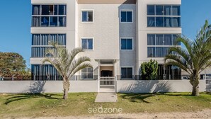 Un edificio residencial moderno de varios pisos con fachada plana, ventanas amplias y entrada con portón.