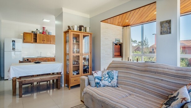 Una sala moderna con sofá, una mesa de comedor con banco, un aparador de madera y un ventanal con vistas al exterior.
