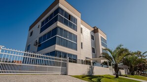 Un edificio moderno de varios pisos con amplios ventanales y una valla blanca en la parte frontal.