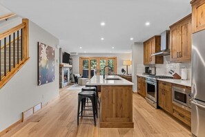 Een moderne keuken met houten kastjes, een centraal eiland en roestvrijstalen apparatuur.