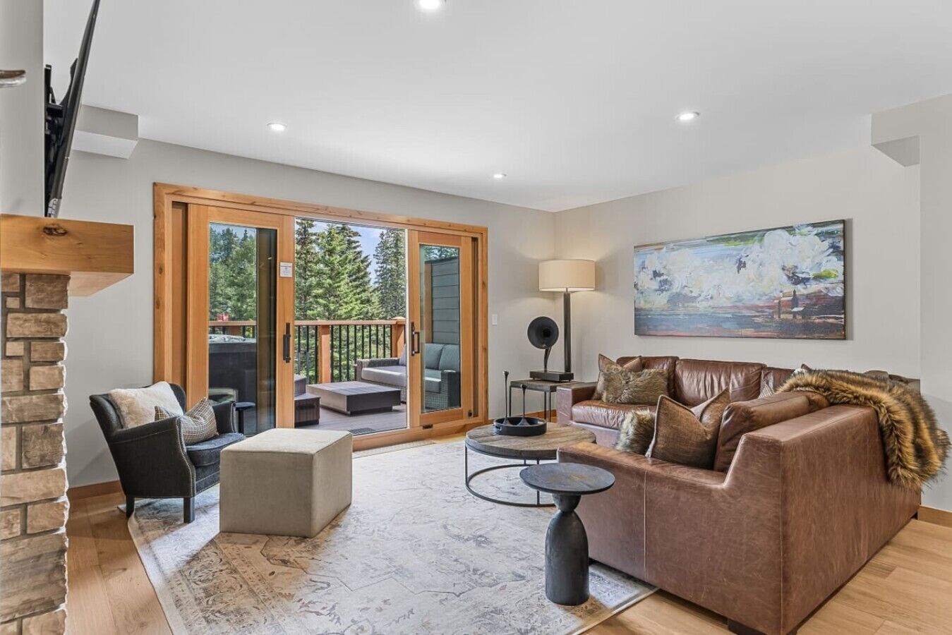 Un salon moderne avec une cheminée, un canapé, une table basse et une vue sur l’extérieur grâce à des portes vitrées.