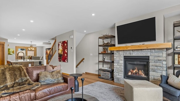 Un salon moderne avec une cheminée, un canapé en cuir et un téléviseur à écran plat.