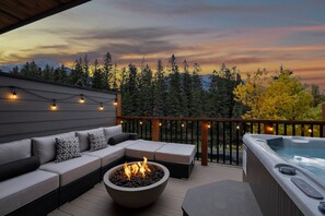 A deck with a fire pit, outdoor seating, and a hot tub.