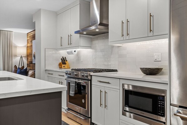 A modern kitchen with stainless steel appliances, white cabinetry, and a built-in oven.