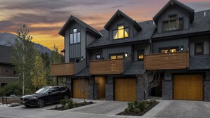A modern multi-story house with a garage, a driveway, and a car parked in front. - Luxury Escape | Private Hot Tub and Firepit (Canmore)